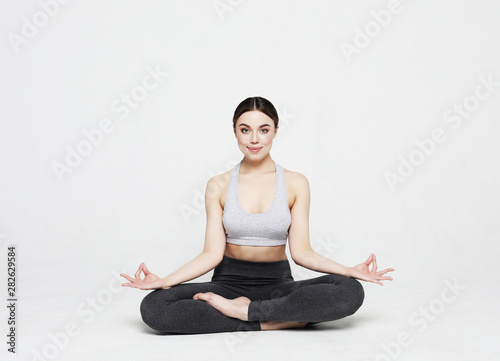 Portrait of attractive woman doing yoga, pilates over light grey background. Healthy lifestyle and sports concept.