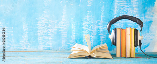 Tableau sur toile audio book concept with open book, row of books an headphones, panorama format o