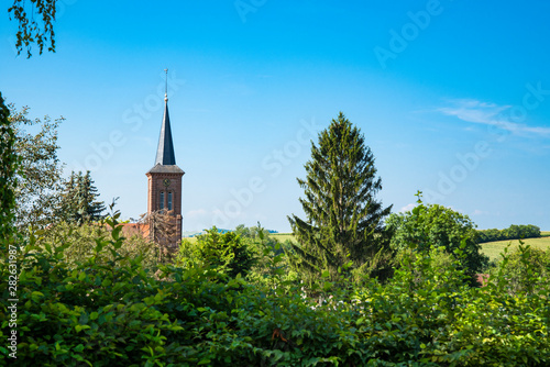 tower of church between green trees, Hunspach, France photo