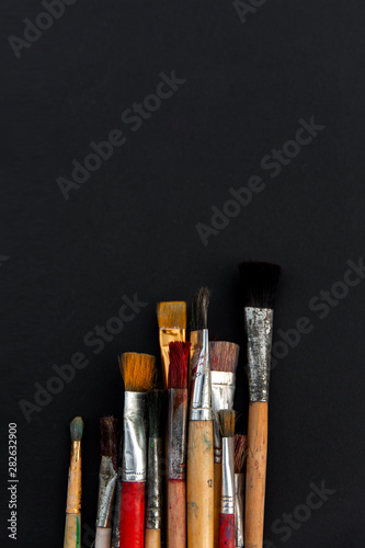 Paint brushes of different sizes on a black background.