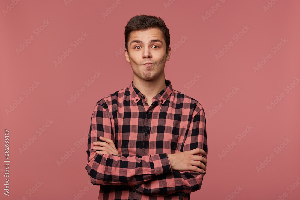 custom made wallpaper toronto digitalYoung handsome wondered guy wears in checkered shirt, looks at the camera with surprised expression, crosed arms, isolated over pink background.