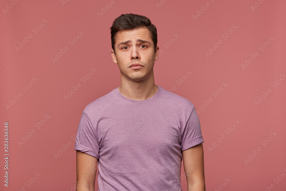 Portrait of young attractive boy in blank t-shirt, stands over pink background and looks sad and unhappy. Portrait of young attractive boy in blank t-shirt, stands over pink background and looks sad and unhappy.