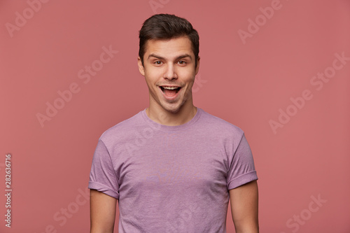 Wallpaper Mural Portrait of cheerful handsome young man wears in blank t-shirt, looks at the camera with happy expression, stands over pink background. Torontodigital.ca