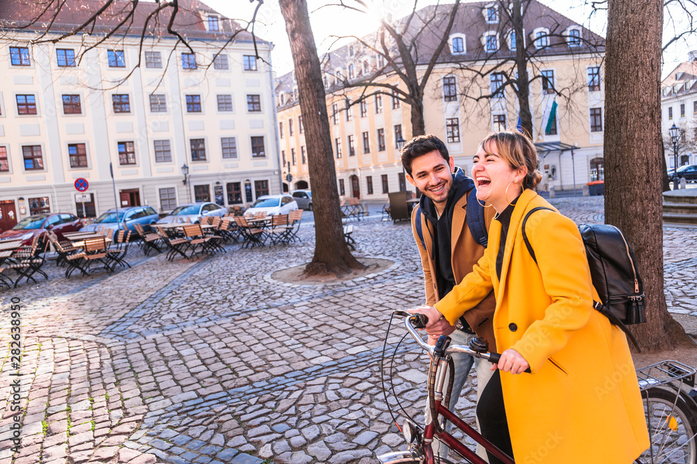 Young latin man walks near woman riding bicycle