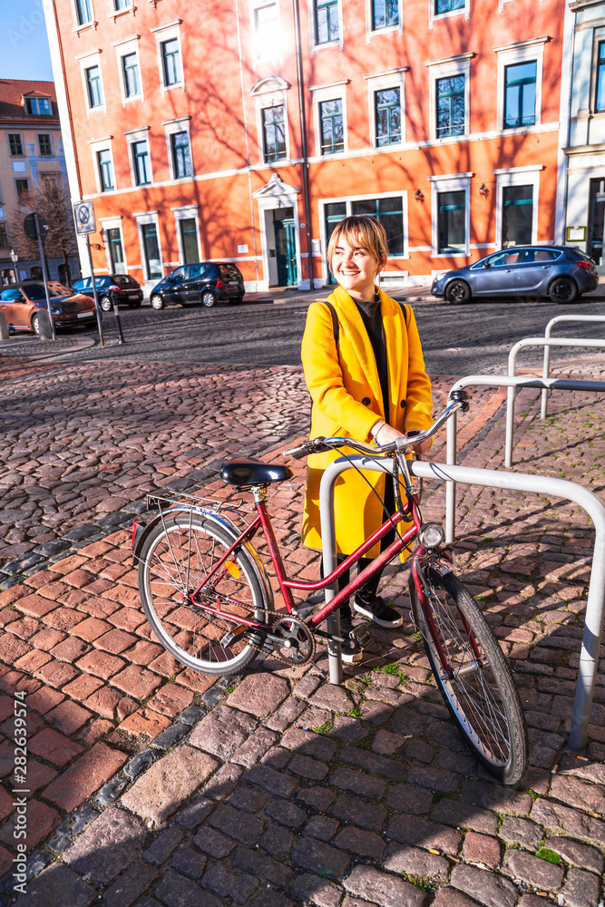 Young girl stands next to parked bike in parking