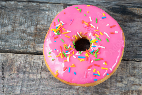 Sweet donut with icing on wooden background