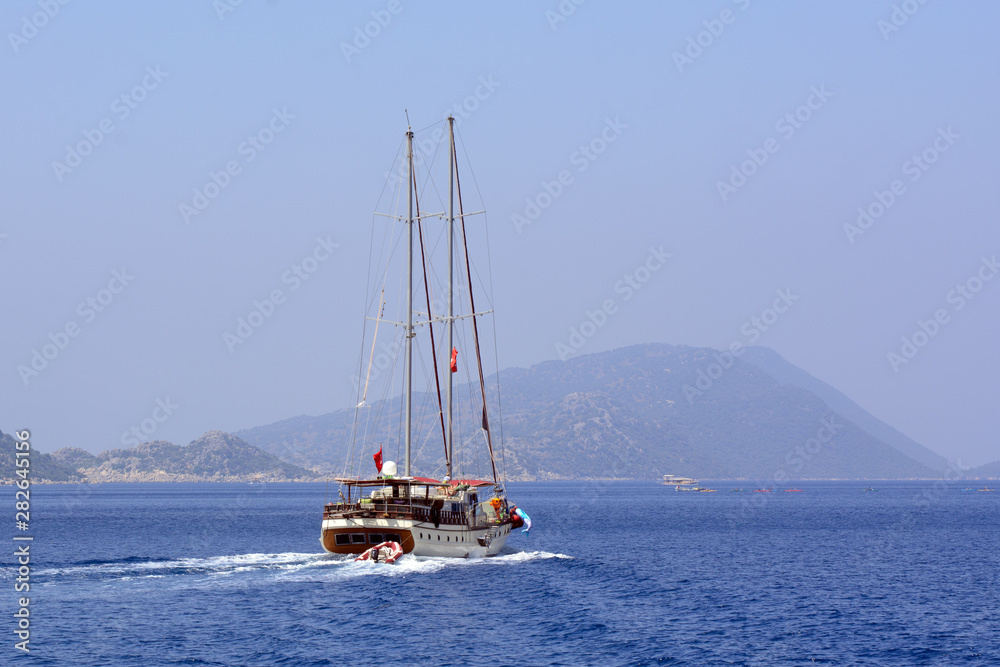Wooden yacht on the Mediterranean sea against the backdrop of the mountains on a clear sunny day. Concept - vacation at sea. Sea tourism. Mediterranean Cruise Wooden yacht on the Mediterranean sea against the backdrop of the mountains on a clear sunny day. Concept - vacation at sea. Sea tourism. Mediterranean Cruise