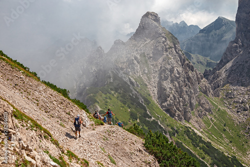 Some hikers go along an impassable rocky path, in view of the towers and peaks of the Friulian Dolomites, in Italy.