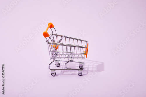 decorative toy shopping cart with orange handle on violet background