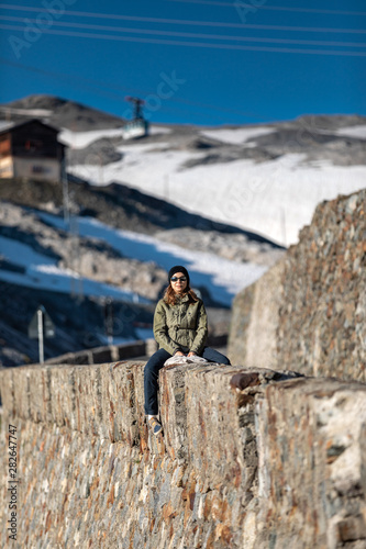 girl sitting in the mountains and looking at the camera. portrait of a girl in nature in a hat and sunglasses. photo