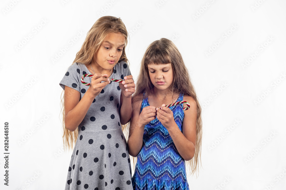Two girls can not open the plastic packaging of caramel candies Two girls can not open the plastic packaging of caramel candies