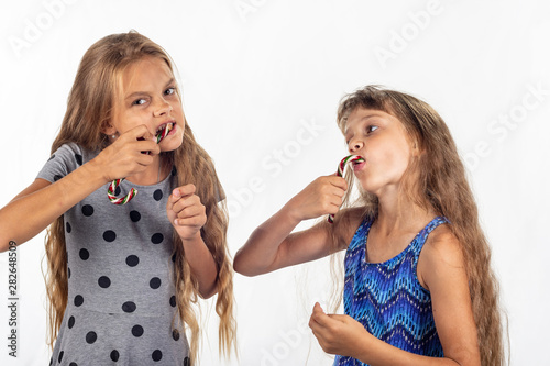Two girls eagerly bite and suck caramel candies