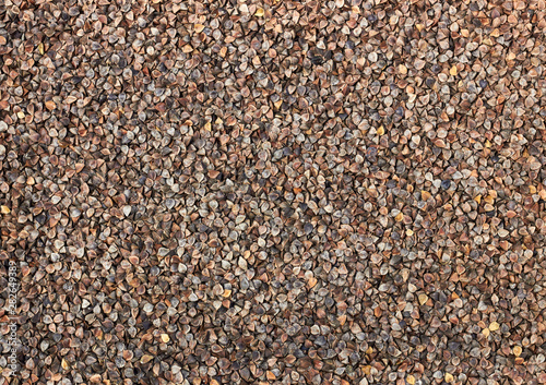 Rough unshelled buckwheat groats textured background pattern for your design, flat lay, from above overhead top view, closeup, macro