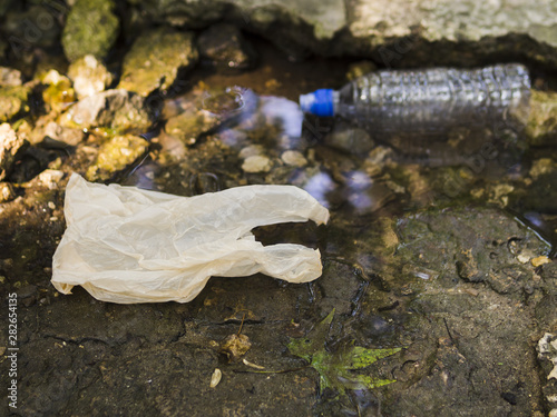 Photos Plastic bag and water bottle near stream