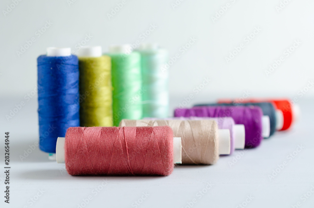 Multi-colored spools of sewing threads close-up. Craft and hobby concept. Multi-colored spools of sewing threads close-up. Craft and hobby concept.