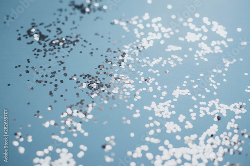 Abstract blue background with silver confetti close up.