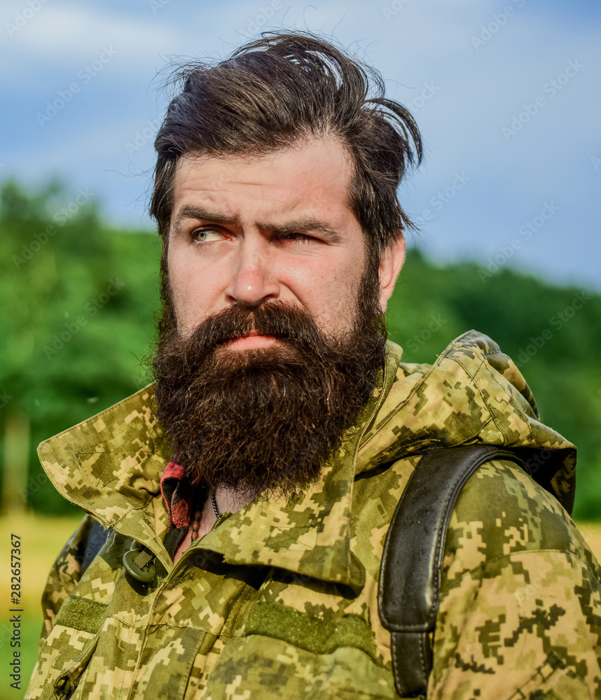 windy weather. Hunter man. Hunting season. soldier in military uniform. brutal male poacher. male beard care. bearded man hiking with backpack. mature hipster with beard in military jacket