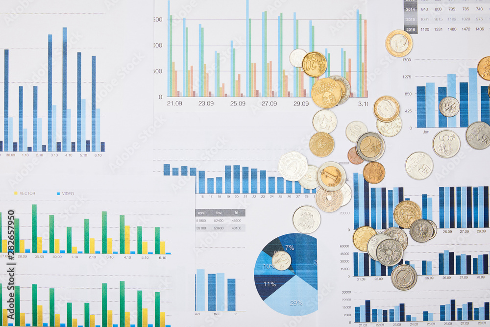 top view of papers with graphs and coins on table top view of papers with graphs and coins on table