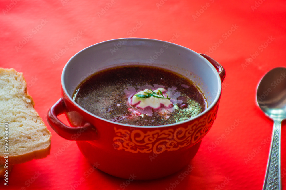 Red soup with vegetables with slices of bread on a pink bright background Red soup with vegetables with slices of bread on a pink bright background