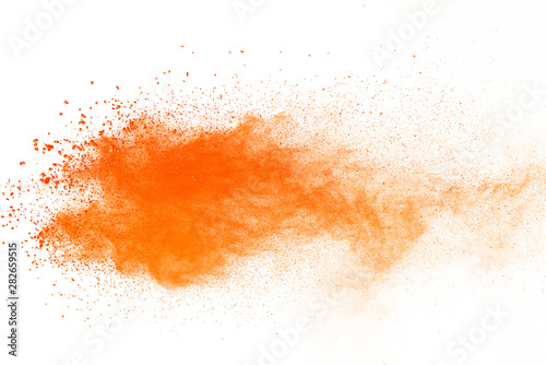 Abstract orange powder explosion. Closeup of orange dust particle splash isolated on white background © piyaphong