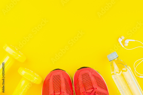 White headphones, yellow dumbbells, a bottle of fresh water