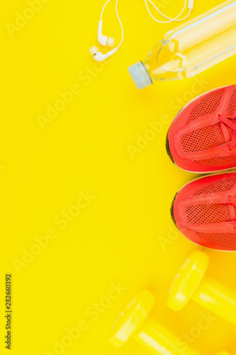 White headphones, yellow dumbbells, a bottle of fresh water