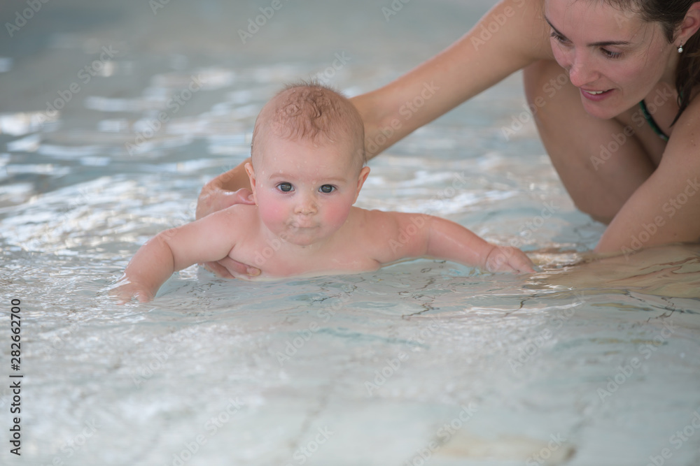 Little cute baby boy, swimming happily in a shallow pool water Little cute baby boy, swimming happily in a shallow pool water