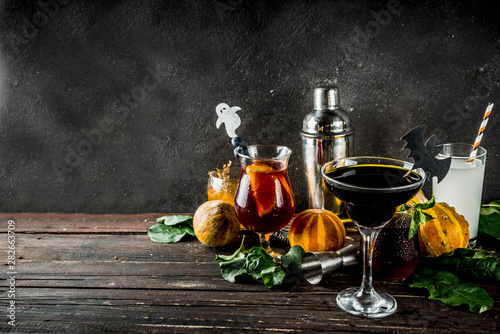Selection of Halloween traditional autumnal alcoholic cocktails and drinks. Different alcoholic beverages and shots for Halloween party, with autumn decorations, on a wooden table