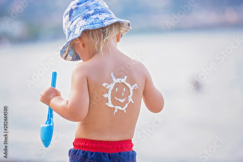 Sweet preschool boy, holding scuba mask with sunscream applied on his back, ready for the harsh sun photo