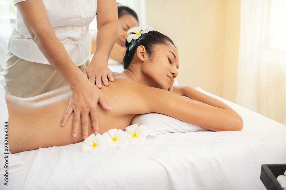 Beautiful young woman getting spa massage salon and white flower on her head. Beautiful young woman getting spa massage salon and white flower on her head.