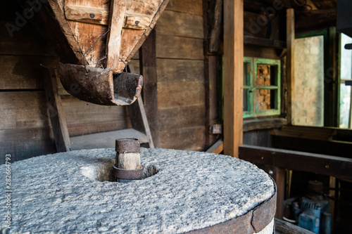 The ancient old stone grain mill gristmill grinding wheat or grains into flour using millstone quern stone in the serbian house photo