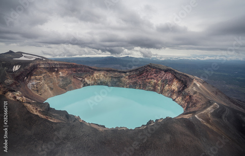 Karymsky Lake, a crater pool located in the Karymsky volcano on the Kamchatka Peninsula, Russia. Radius 5 km. Toxic gases turned this into the large acid lakes. Aquamarine blue poisonous basin.
