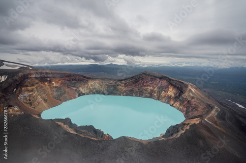 Karymsky Lake, a crater pool located in the Karymsky volcano on the Kamchatka Peninsula, Russia. Radius 5 km. Toxic gases turned this into the large acid lakes. Aquamarine blue poisonous basin.