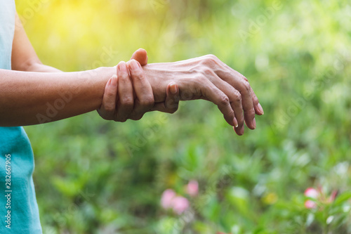 closeup hand of person holding arm his fill pain on for healthy concept on nature background. © mintra