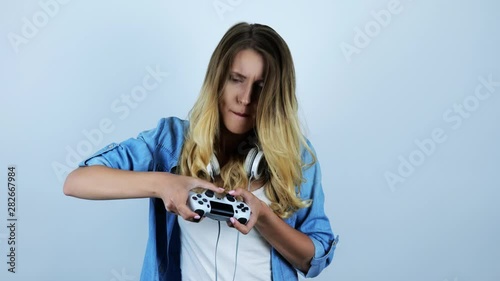 young beautiful sexy blonde woman with headphones on her neck playing video game looking excited on isolated white background photo