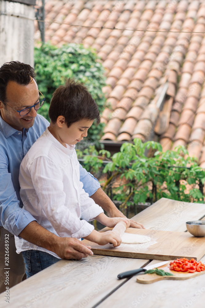 Father and son preparing pizza together Father and son preparing pizza together