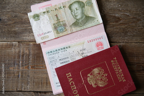 A Russian passport with a Chinese visa and money is one yuan. Visa stamp, passport. Vacation and travel concept. Top view.