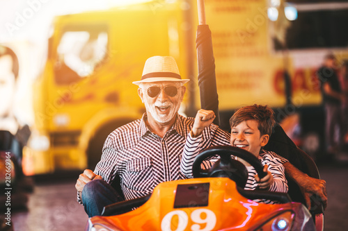 Konstfotografi Grandfather and grandson having fun and spending good quality time together in amusement park