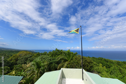 Flag of Jamaica waving against blue sky. Flag of Jamaica have a gold saltire on a green and black field. photo