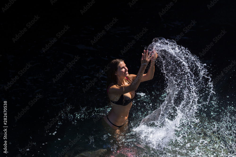 Young woman in bikini splashing sea water