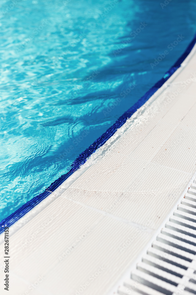 Fototapeta premium Blue water with light reflection at the edge of the curved swimming pool. The concept of summer travel and recreation