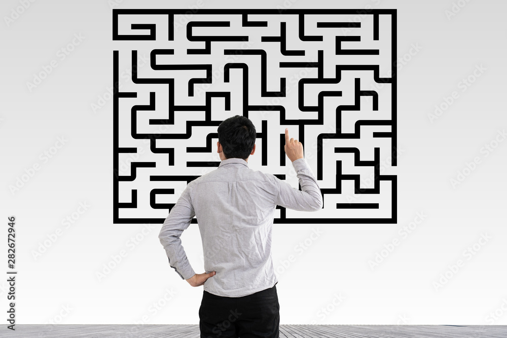 Businessman in doubt looking to a maze and searching the way out Businessman in doubt looking to a maze and searching the way out