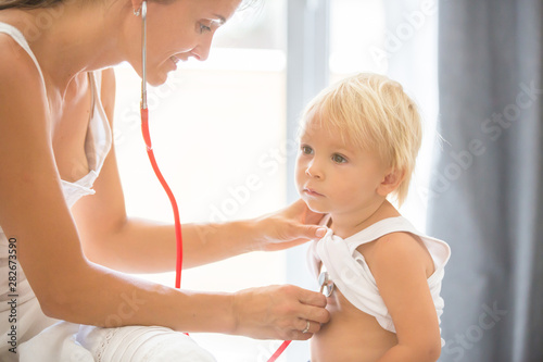 Pediatrician examining baby boy. Doctor using stethoscope to listen to kid and checking heart