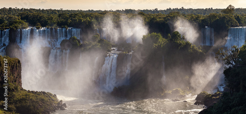 Beautiful view of waterfalls on Iguazu river in sunny summer day. Foz de iguaçu divides the border between Brazil and Argentina and is One of the Seven Wonders of the World.
