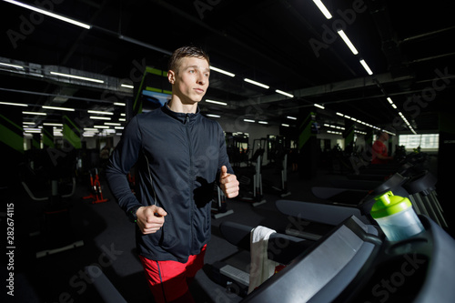 Jogger wearing sportswear running on treadmill at gym