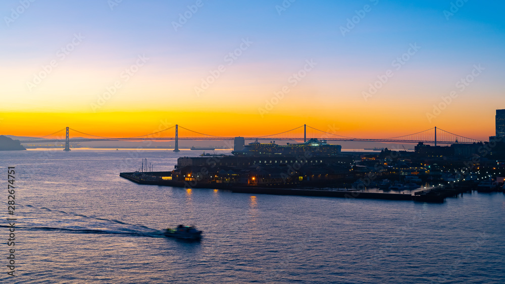Cold summer morning sunrise with the iconic Oakland Bay Bridge and a Cruise Ship in port, San Francisco, California. Famous travel location landmark on the west coast.