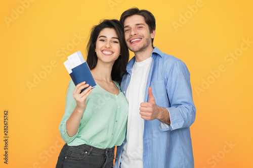 Loving couple ready for travel, showing passport and thumb up