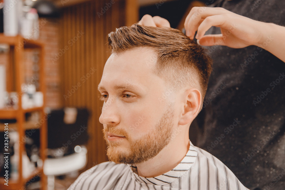 Fototapeta premium Barber master hairdresser does style with scissors and comb. Concept Barbershop