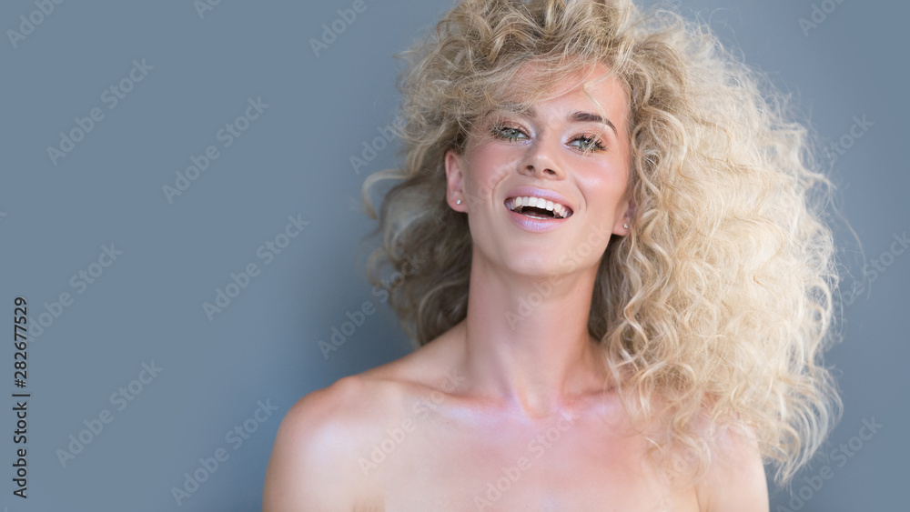 Portrait positive emotional young beautiful girl model with blond curly hair shouts loudly, expresses excited feelings, being under impression. Concept creative glamorous photo. Gray studio background Portrait positive emotional young beautiful girl model with blond curly hair shouts loudly, expresses excited feelings, being under impression. Concept creative glamorous photo. Gray studio background