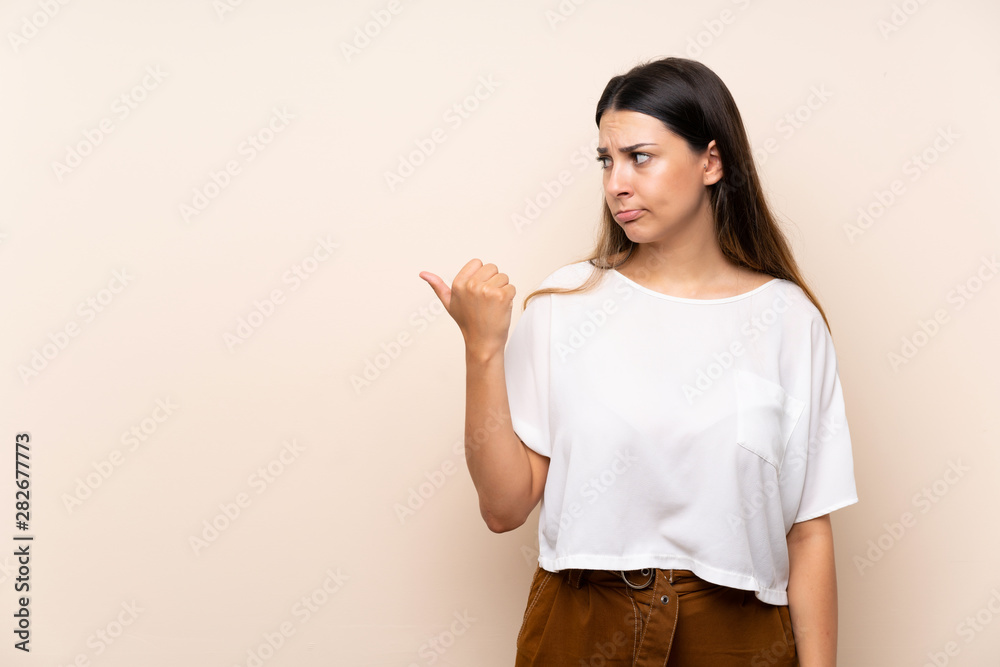 Young brunette woman over isolated background unhappy and pointing to the side Young brunette woman over isolated background unhappy and pointing to the side